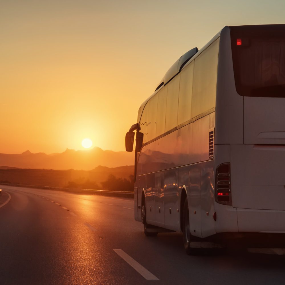 White,Bus,Driving,On,Road,Towards,The,Setting,Sun