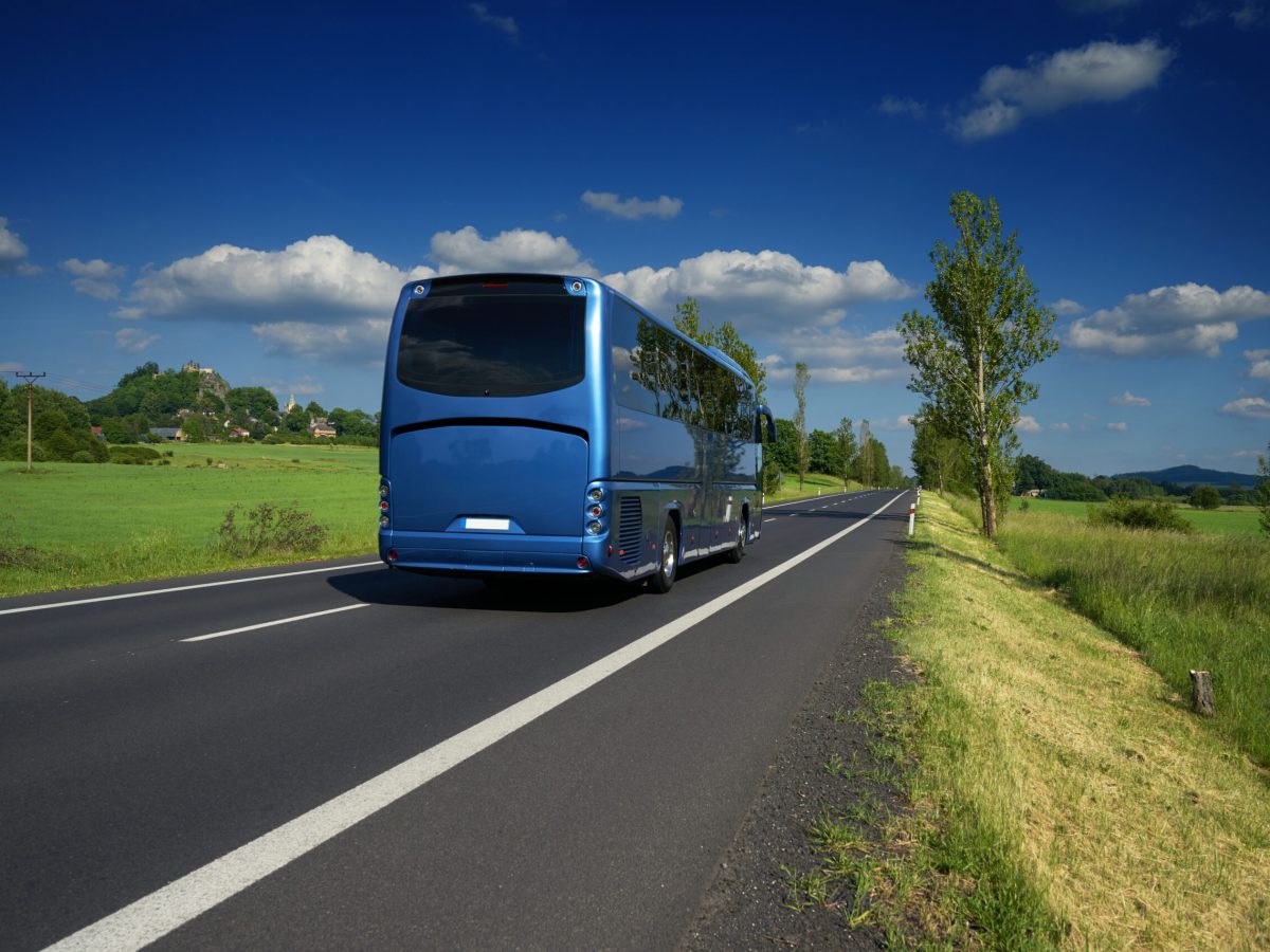 Blue,Bus,Traveling,On,Asphalt,Road,In,A,Rural,Landscape.